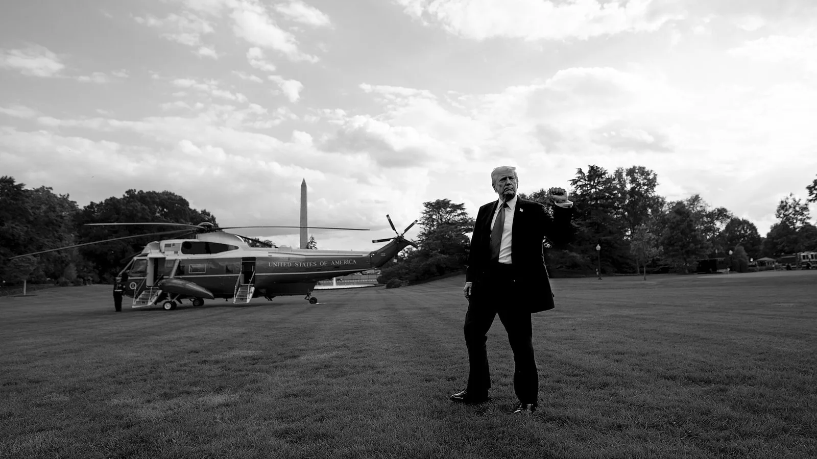 Donald Trump, com o punho erguido, no gramado sul da Casa Branca, com o helicóptero presidencial Marine One e o Monumento a Washington ao fundo, em setembro de 2025 (imagem de arquivo, em preto e branco)