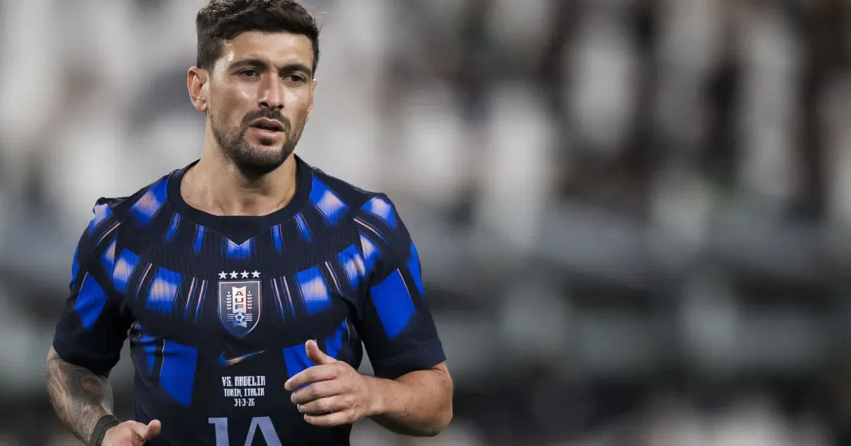 Jogador em uniforme azul e preto com escudo de seleção nacional em partida de futebol