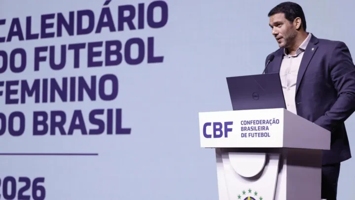 Homem de terno escuro fala em púlpito da CBF diante de tela com o título "Calendário do Futebol Feminino do Brasil 2026