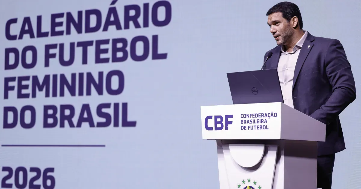 Homem de terno escuro fala em púlpito da CBF diante de tela com o título "Calendário do Futebol Feminino do Brasil 2026