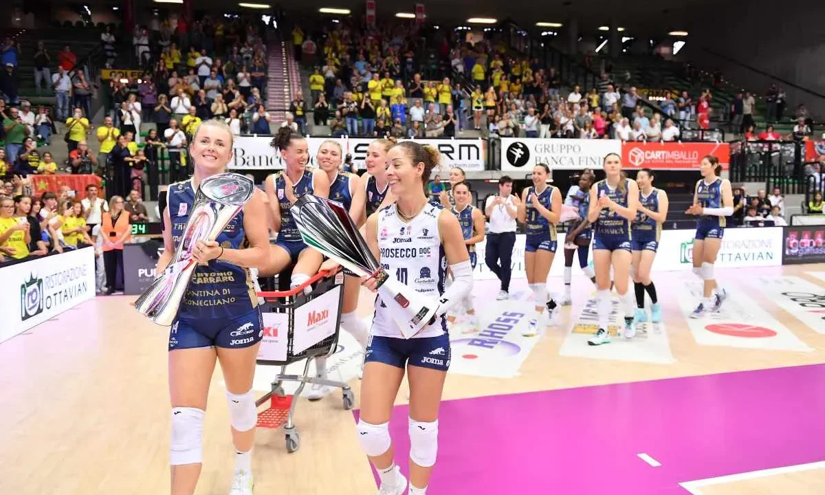 Atletas de voleibol feminino exibem troféus após vitória em partida disputada em ginásio com arquibancadas repletas de torcedores
