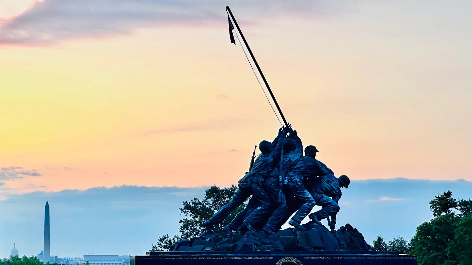 Silhueta da estátua de bronze do Memorial de Guerra dos Fuzileiros, em Arlington, ao nascer do sol, com o Monumento a Washington ao fundo, em 2025