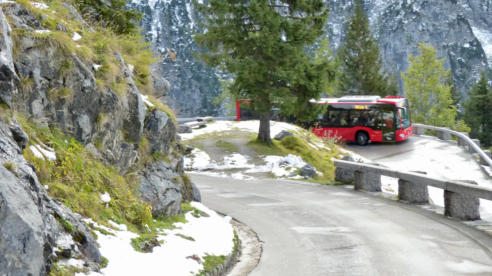 Ônibus vermelho numa curva da Kehlsteinstraße, estrada estreita de montanha com neve na beira, que leva ao Kehlsteinhaus, em outubro de 2016 (imagem de arquivo)