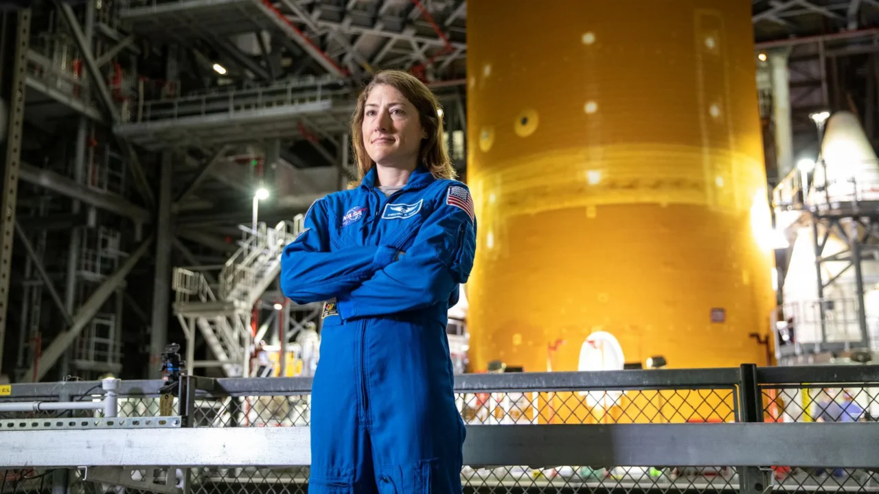 A astronauta da NASA Christina Koch posa dentro do Prédio de Montagem de Veículos (Vehicle Assembly Building) do Kennedy Space Center em 14 de julho de 2021, em frente ao foguete Sistema de Lançamento Espacial (SLS) da agência que acabou impulsionando a espaçonave Orion na missão Artemis I. Koch