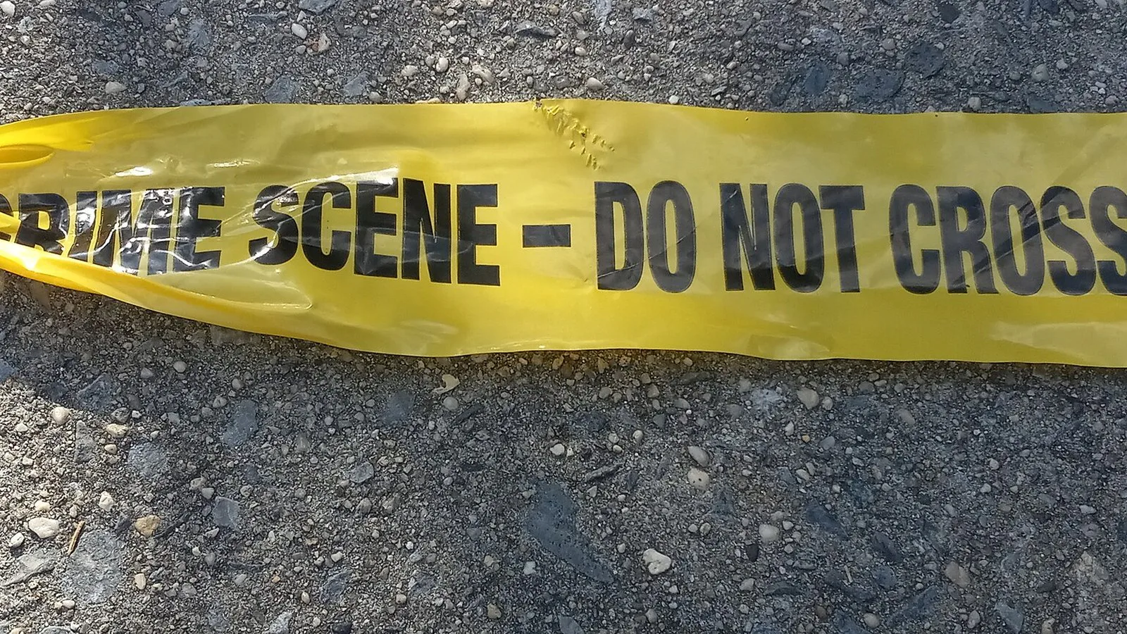 Fita amarela de cena de crime da polícia de Nova York com o aviso "Crime scene, do not cross" estendida sobre o asfalto, em 2024 (imagem ilustrativa)