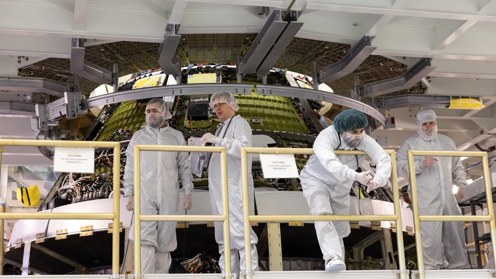 Engenheiros com roupas de sala limpa terminam de conectar os módulos da tripulação e de serviço da Orion da Artemis III, em 31 de julho de 2026, no prédio de operações Neil A. Armstrong, no Centro Espacial Kennedy