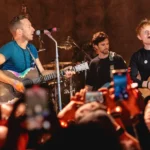 Ed Sheeran se apresenta ao vivo em show, enquanto o público registra o momento com celulares