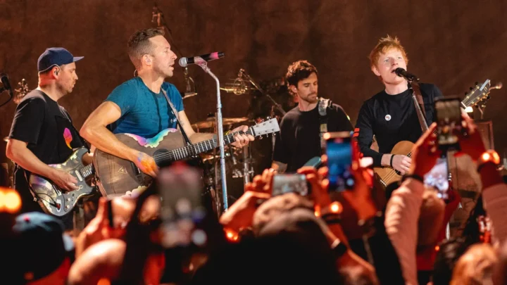 Ed Sheeran se apresenta ao vivo em show, enquanto o público registra o momento com celulares