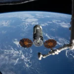 A espaçonave de carga Cygnus XL, da Northrop Grumman, repousa em seu ponto de captura em 13 de abril de 2026, a 12 metros da Estação Espacial Internacional, enquanto o braço robótico Canadarm2 se prepara para capturar a nave de reabastecimento.