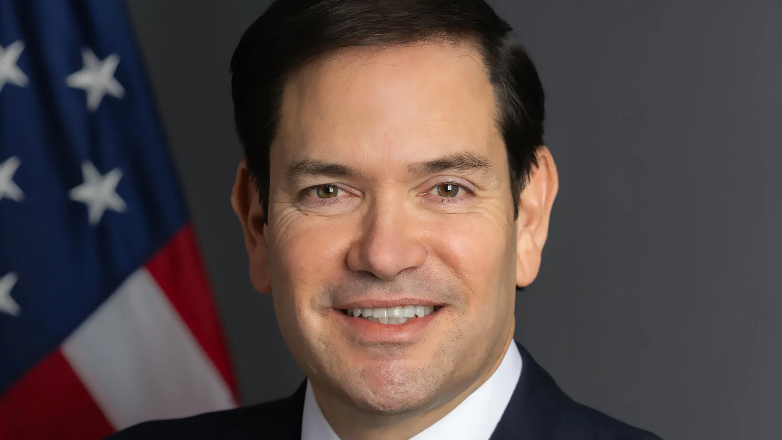 Retrato oficial de Marco Rubio, secretário de Estado dos EUA, sorrindo diante da bandeira americana, em janeiro de 2025