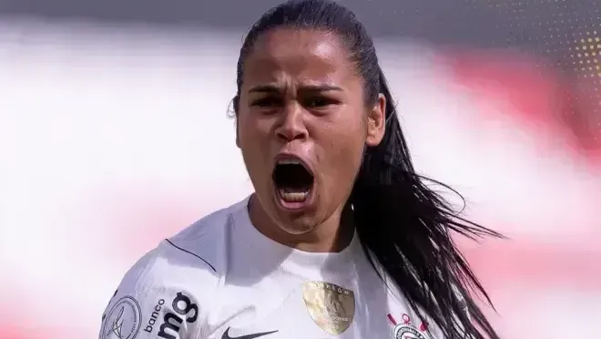 Jogadora do Corinthians com camisa branca, gritando de forma intensa durante uma partida de futebol feminino