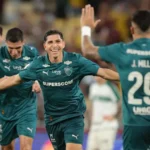 Jogadores de camisa verde comemoram um gol de braços abertos, com um jogador de costas erguendo as mãos e o uniforme trazendo o nome J. Millan, número 29