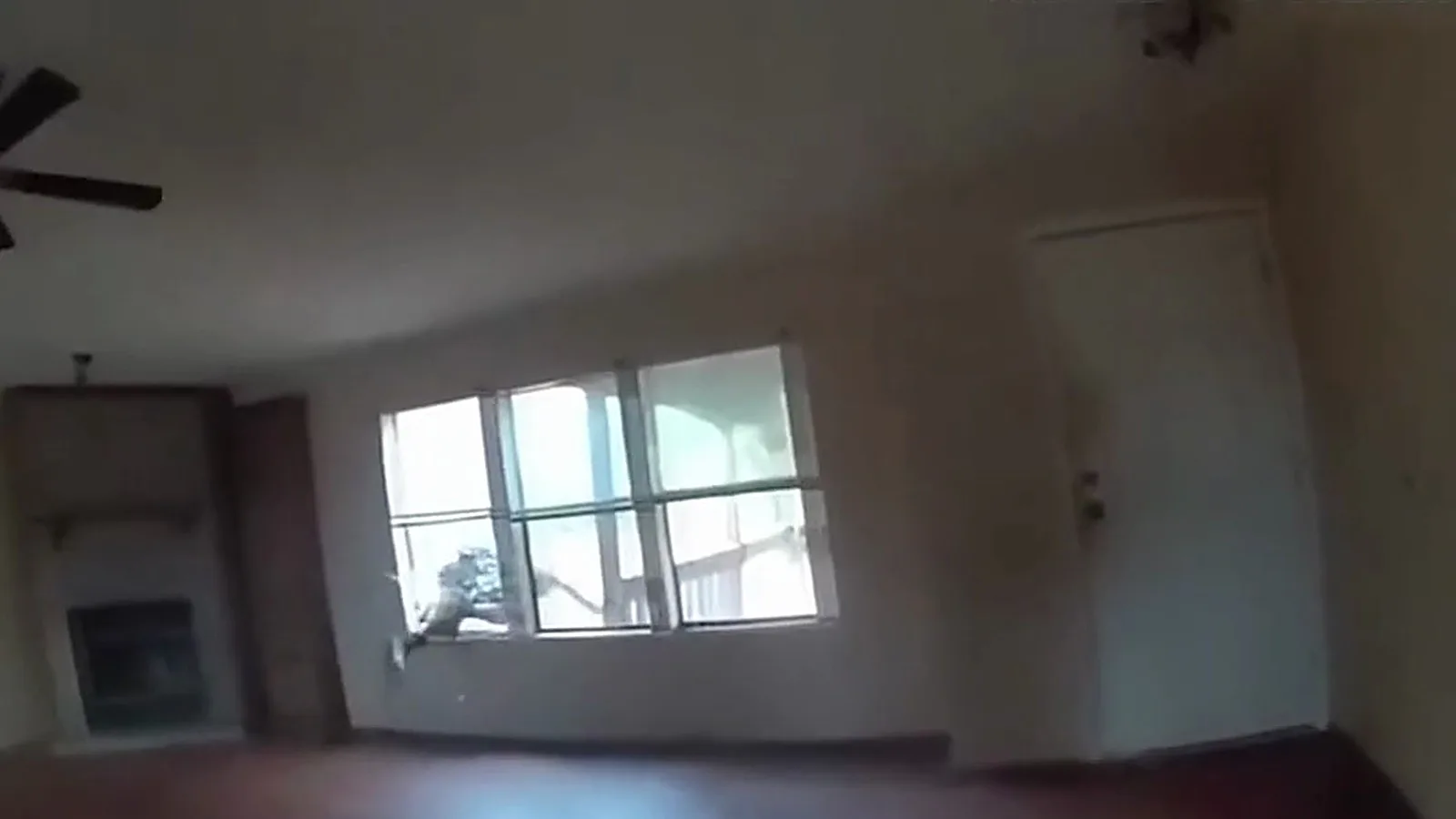 Sala vazia da casa vista pela câmera do policial no instante em que o suspeito sai pela janela