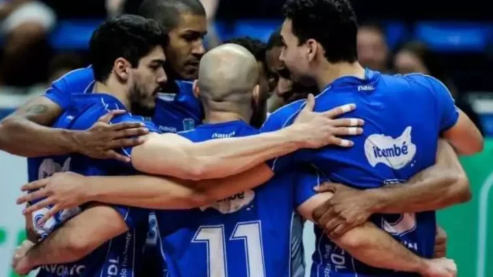 Jogadores de vôlei em uniforme azul formam roda no centro da quadra durante partida do Campeonato Mineiro Masculino