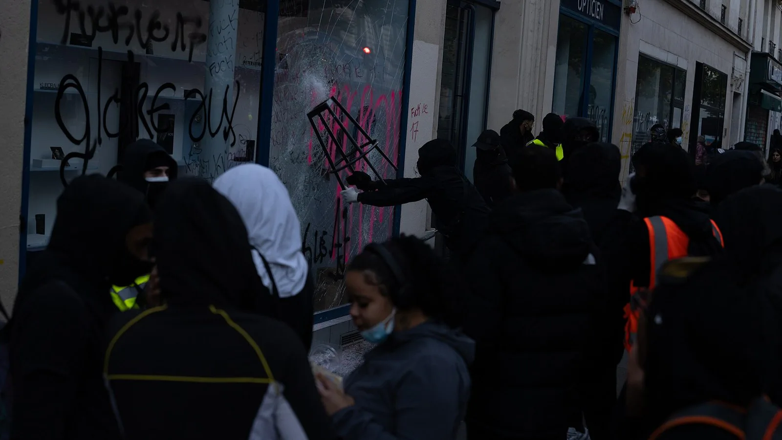 Grupo de encapuzados diante de uma vitrine quebrada e pichada em Paris, em 17 de outubro de 2026
