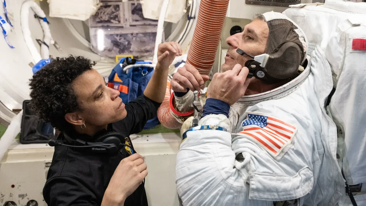 A astronauta da NASA Jessica Watkins auxilia o astronauta da NASA Luke Delaney enquanto ele pratica como vestir um traje espacial em um simulador de câmara de descompressão da Estação Espacial Internacional em 5 de maio de 2026, na Instalação de Maquetes de Veículos Espaciais do Centro Espacial