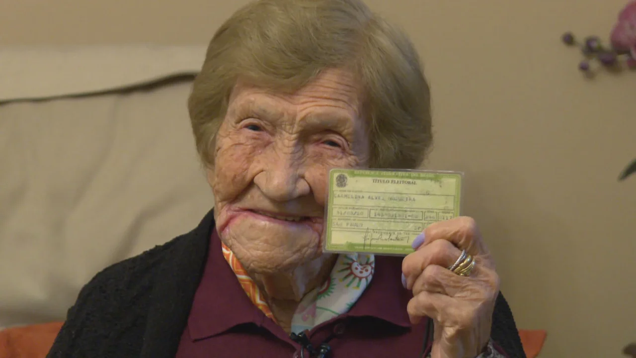Carmelina Alves Nogueira, de 106 anos, exibe o título de eleitor neste domingo (4), em São Paulo. Moradora do Jaguaré, na Zona Oeste, ela nasceu antes da criação da Justiça Eleitoral (1932) e fez questão de comparecer às urnas acompanhada da neta, tendo prioridade por ser idosa.