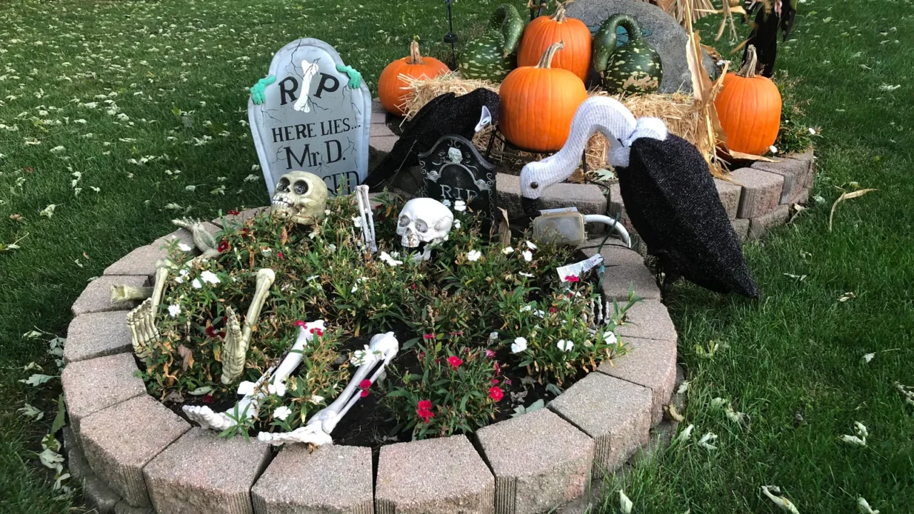 Canteiro de jardim decorado para o Halloween, com lápide, esqueletos, abóboras e urubus de enfeite (imagem ilustrativa)