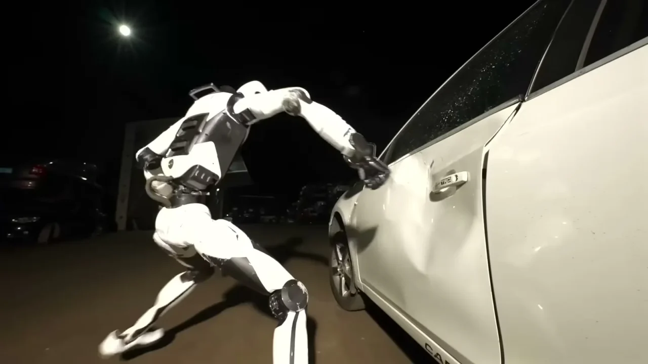 Robô humanoide branco H2-X, da Unitree, golpeia a porta de um carro branco à noite, em cena do vídeo de lançamento