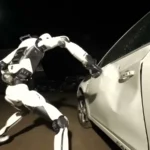Robô humanoide branco H2-X, da Unitree, golpeia a porta de um carro branco à noite, em cena do vídeo de lançamento