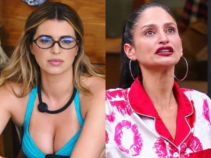 Duas mulheres lado a lado: à esquerda, uma loira de óculos e top azul; à direita, uma morena de cabelo preso, brincos de argola e pijama vermelho e branco com estampa de batom