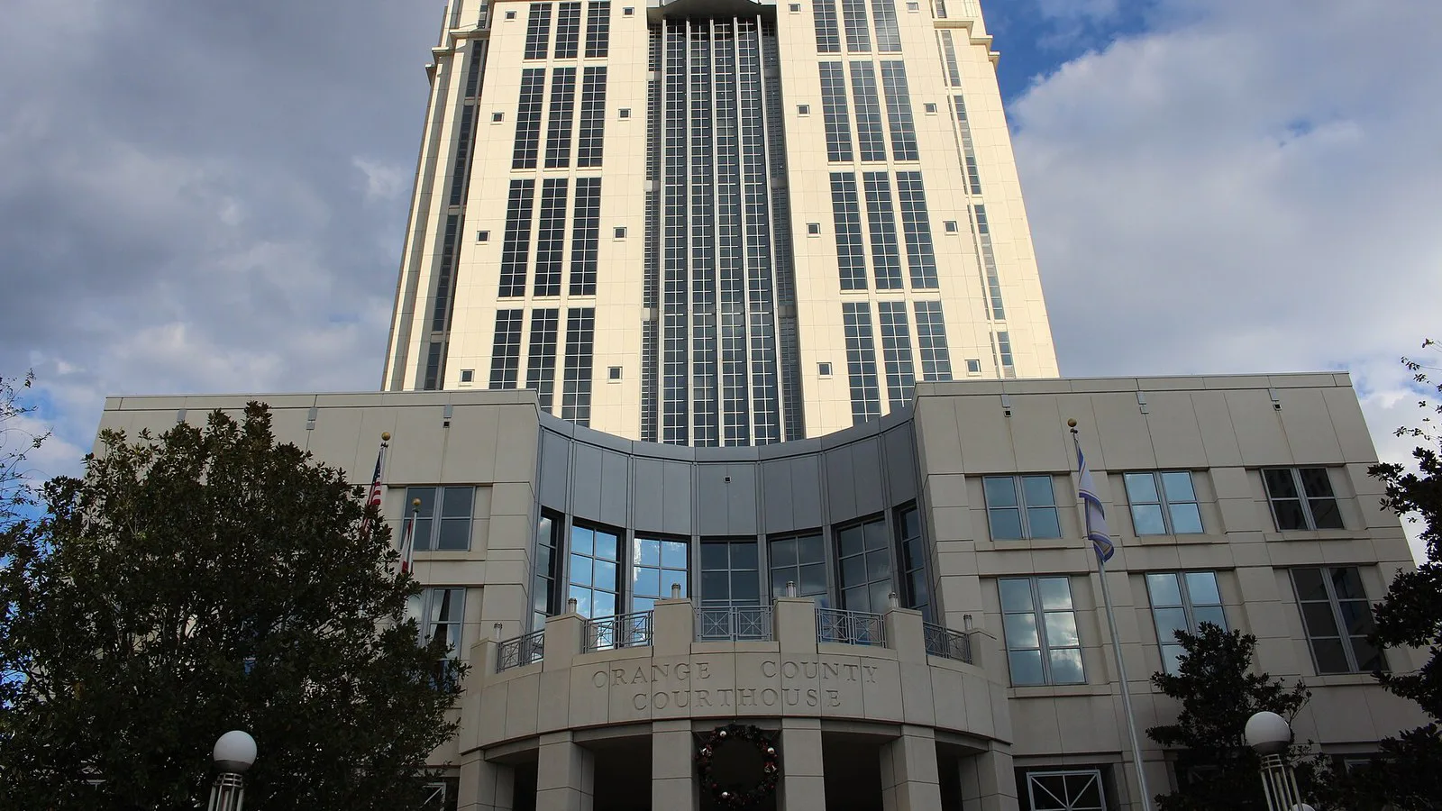Fachada do fórum do condado de Orange, em Orlando, com a torre do prédio ao fundo e o nome "Orange County Courthouse" na entrada