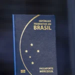 Passaporte brasileiro azul, modelo lançado em 2015, em pé contra um fundo escuro (imagem de arquivo)