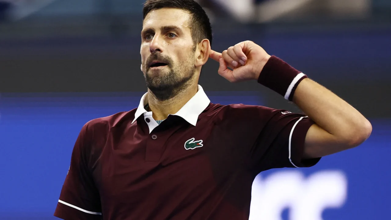 Tenista em quadra durante partida do ATP 500 de Pequim, vestindo polo bordô com detalhes brancos e pulseira de suor roxa