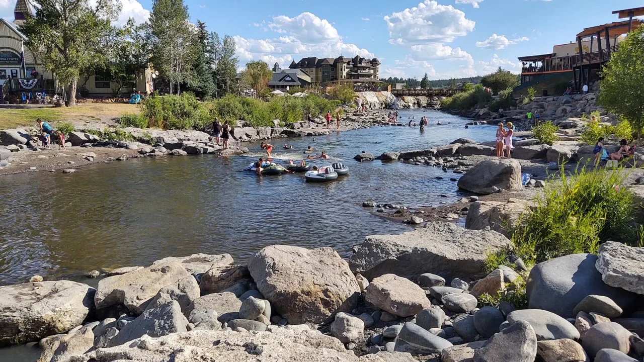 Rio San Juan correndo entre pedras no centro de Pagosa Springs, no Colorado, com pessoas em boias e prédios na margem, em dia de verão de 2020 (imagem de arquivo)