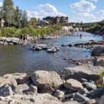 Rio San Juan correndo entre pedras no centro de Pagosa Springs, no Colorado, com pessoas em boias e prédios na margem, em dia de verão de 2020 (imagem de arquivo)