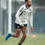 Jogador do Santos em movimento durante treino no Centro de Treinamento Rei Pelé, usando uniforme branco e azul da equipe