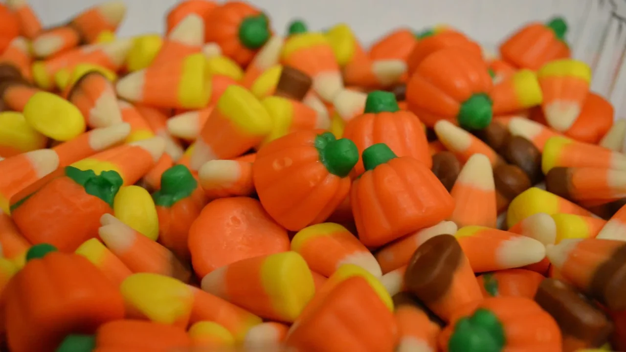 Foto de arquivo de balas de milho (candy corn) e balas em forma de abóbora, nas cores laranja, amarelo e branco, amontoadas em primeiro plano