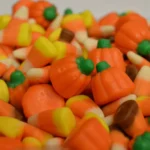 Foto de arquivo de balas de milho (candy corn) e balas em forma de abóbora, nas cores laranja, amarelo e branco, amontoadas em primeiro plano