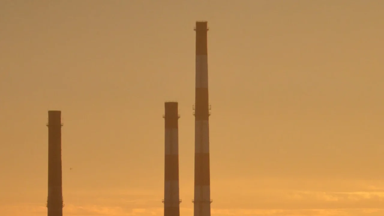 As três chaminés da usina EC-2 contra o céu laranja da tarde em Łódź, na Polônia, em setembro de 2021 (imagem de arquivo)