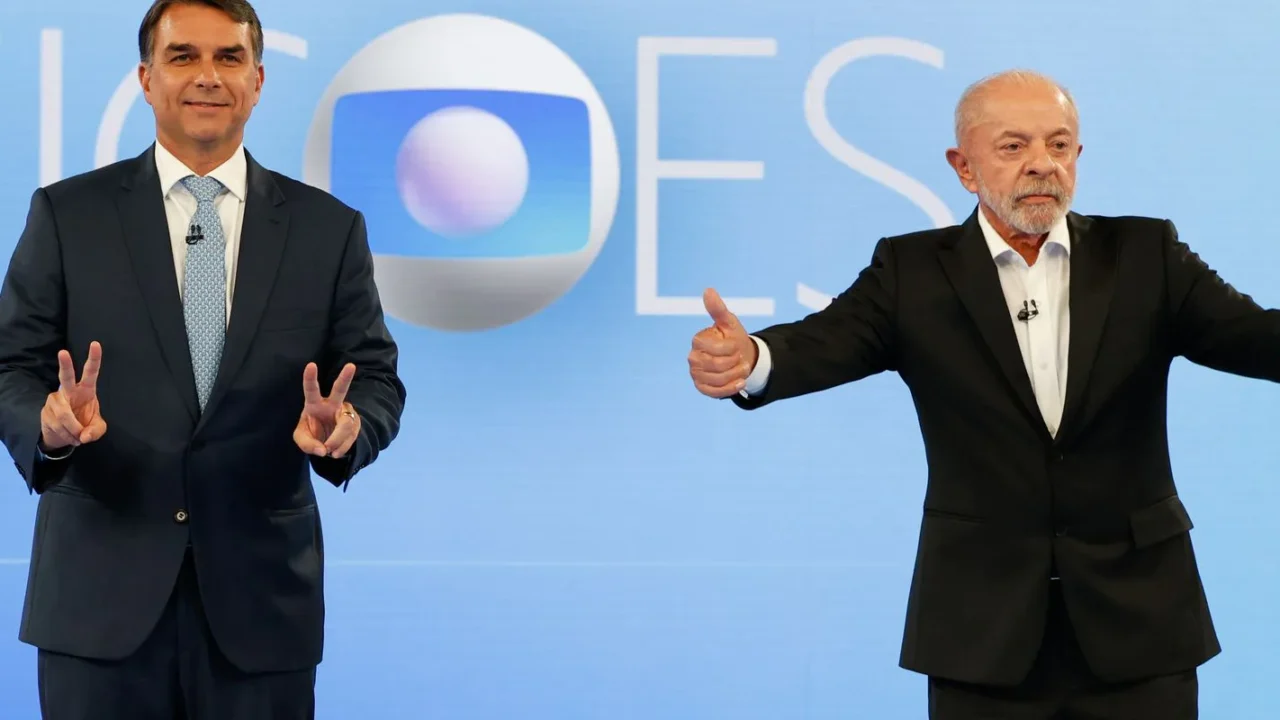 Flávio Bolsonaro, à esquerda, e Lula, à direita, gesticulam para os fotógrafos no cenário do debate da TV Globo, no Rio de Janeiro, em 23 de outubro de 2026