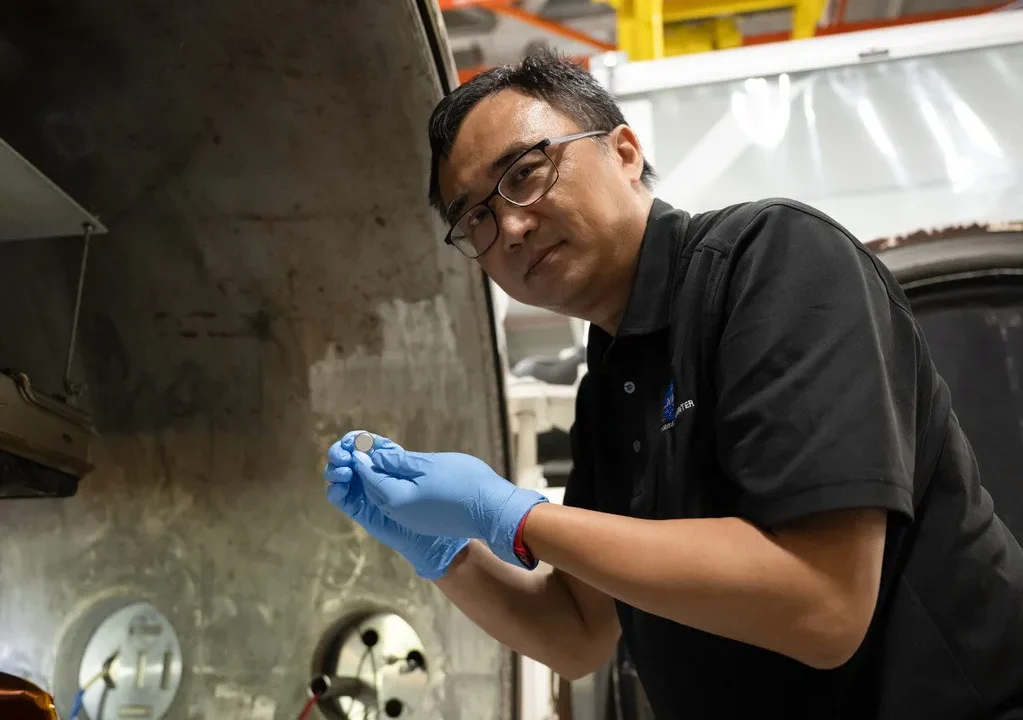 Yi Lin, líder de testes e pesquisa do SPEARS no NASA Langley, segura uma das pequenas baterias de célula tipo moeda que tinham acabado de passar por testes de vácuo térmico.