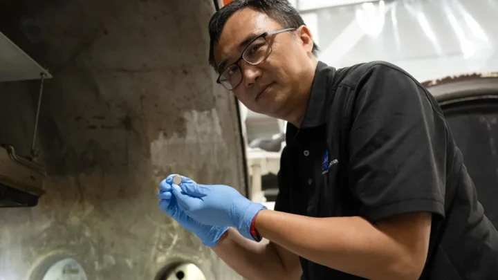 Yi Lin, líder de testes e pesquisa do SPEARS no NASA Langley, segura uma das pequenas baterias de célula tipo moeda que tinham acabado de passar por testes de vácuo térmico.