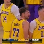 Jogadores do Lakers comemoram durante a partida contra o Golden State Warriors, com o placar de 66 a 52 exibido na parte inferior da tela