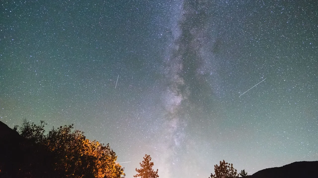 Meteoros cruzam o céu durante a chuva de meteoros Oriônidas de 2017, com a Via Láctea visível no alto.