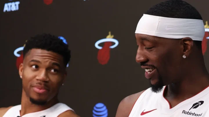 Dois jogadores de camisa branca do Miami Heat sorriem em entrevista coletiva, um deles de faixa branca na cabeça, diante de um painel com o logo da equipe e da AT&T