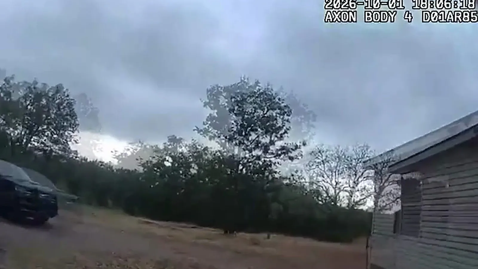 Do lado de fora da casa, a câmera do policial mostra o terreno e a viatura durante a busca pelo suspeito