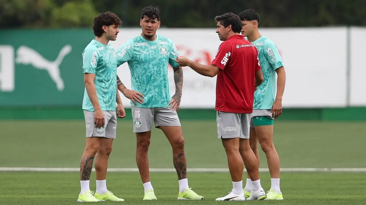 Jogadores do Palmeiras conversam durante treinamento em campo, com um integrante da comissão técnica orientando o grupo
