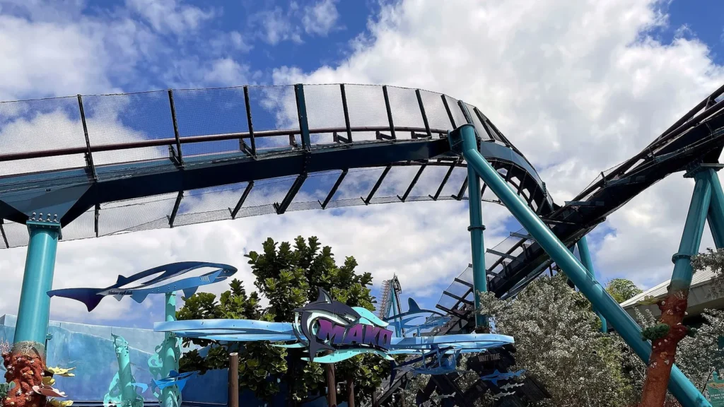 Placa de entrada da Mako, decorada com esculturas de tubarões, sob os trilhos e as colunas azul-esverdeadas da montanha-russa, no SeaWorld Orlando, em março de 2021 (imagem de arquivo)