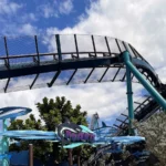 Placa de entrada da Mako, decorada com esculturas de tubarões, sob os trilhos e as colunas azul-esverdeadas da montanha-russa, no SeaWorld Orlando, em março de 2021 (imagem de arquivo)