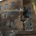 Bombeiros em plataforma de escada inspecionam fachada de escola atingida por drone no distrito de Solomianskyi, em Kiev, em 1º de outubro de 2026, outro ataque em que alunos e funcionários estavam no abrigo